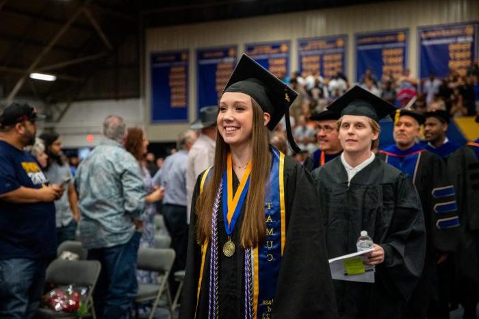 一名女学生微笑着走在毕业典礼的红毯上